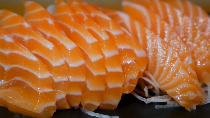 Close-up of fresh salmon sashimi slices on shredded radish