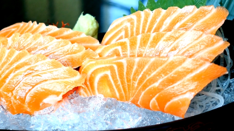 Close-up of fresh salmon sashimi slices served on ice with wasabi