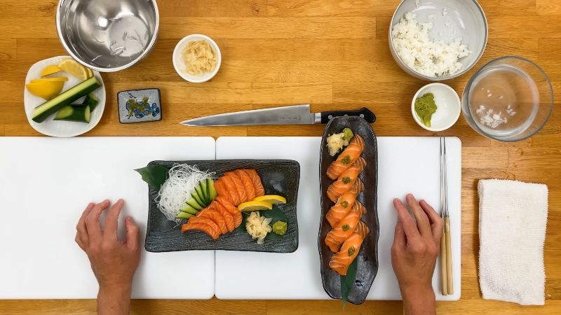 A top view of salmon sashimi and sushi served with cucumber, lemon, wasabi, and ginger