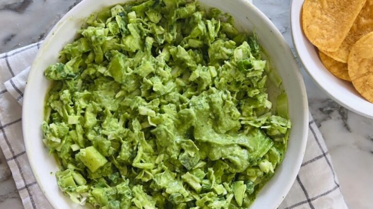 Green Goddess Salad in a white bowl, coated in creamy green dressing and served next to a plate of tortilla chips